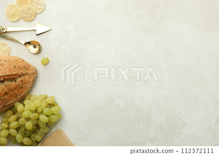 Bread, grapes, book and cutlery on light background, space for text 112372111
