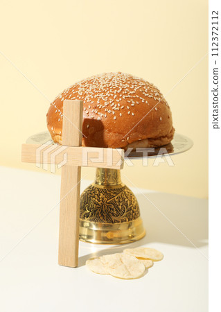 Wooden cross and bread on table on beige background 112372112