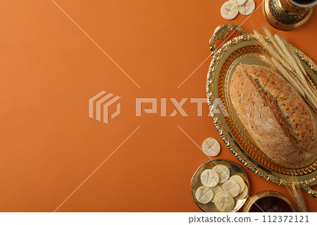 Bread on golden tray and spikelets on orange background, space for text Bread on golden tray and spikelets on orange background, space for text 112372121
