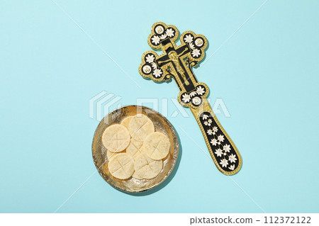 Golden cross and liturgical bread on golden plate on blue background, top view 112372122