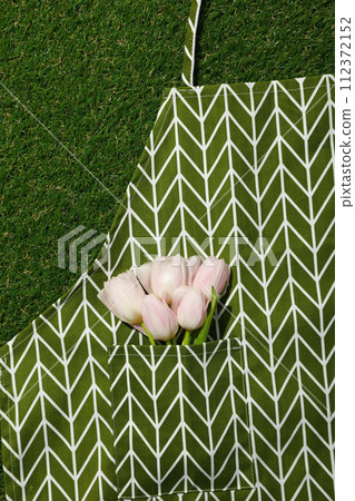 Tulips in apron on green background, top view 112372152