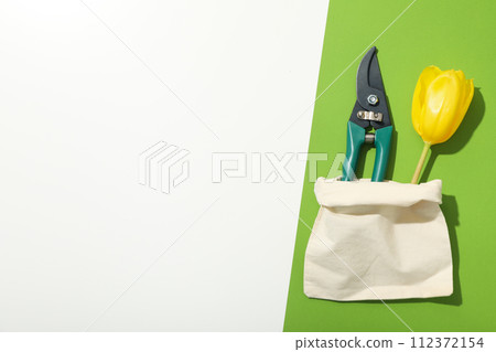 Gardening tool and tulip in cotton bag on green and white background, space for text Gardening tool and tulip in cotton bag on green and white background, space for text 112372154