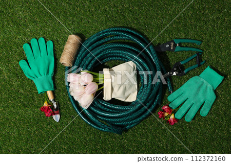 Gardening supplies and flowers in bag on green background, top view 112372160