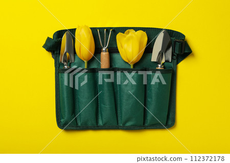 Garden tools and tulips in case on yellow background, top view 112372178