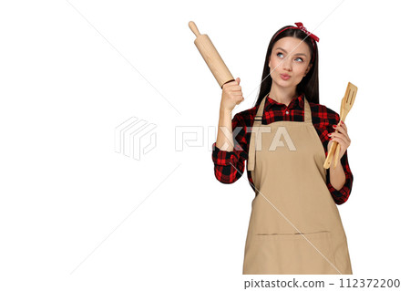Housewife girl with kitchen utensils in her hands, on a gray background. 112372200