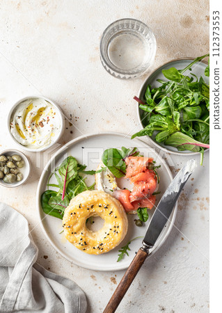 Homemade bagel sandwich with smoked salmon, cream cheese, capers and spinach for healthy breakfast top view 112373553