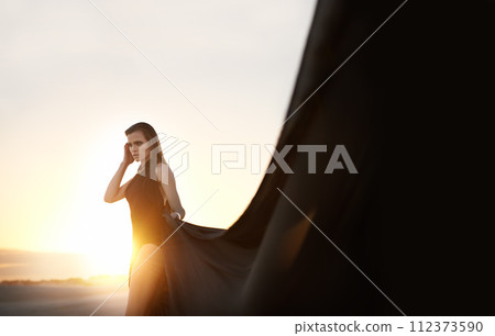 Sunset, woman and fabric in wind outdoor for summer holiday, vacation or travel. Fashion, person and silk in the air for freedom, adventure and breeze in nature with serious girl thinking on mockup Sunset, woman and fabric in wind outdoor for summer holiday, vacation or travel. Fashion, person and silk in the air for freedom, adventure and breeze in nature with serious girl thinking on mockup 112373590