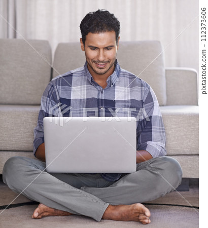 Man, student and internet for laptop on floor of living room, education and scroll or browse on website. Male person, happy and online for information or home for app, sitting and elearning on tech 112373606