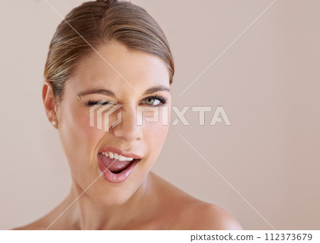 Portrait, wink and skincare of woman in makeup at spa facial treatment to shine. Face, beauty and model in cosmetics for glow, health or wellness isolated on a brown studio background mockup space Portrait, wink and skincare of woman in makeup at spa facial treatment to shine. Face, beauty and model in cosmetics for glow, health or wellness isolated on a brown studio background mockup space 112373679