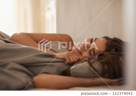 Relax, happy and woman in bed at her home on weekend morning for calm, rest or sleeping. Confident, smile and young female person laying with duvet blanket in bedroom at apartment in Canada. 112374042