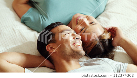 Happy couple, bedroom and talking while lying on bed for love and marriage bonding happiness in comfy home. Asian man and woman joke and relax in romantic hotel together in morning from above 112374308