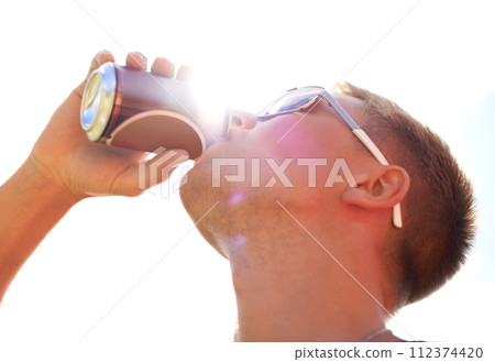 Man, drinking and beer with sunlight outdoor for concert, event or music festival with sunglasses and lens flare. Person, alcohol and beverage in summer for relax, freedom and enjoyment with sunshine 112374420