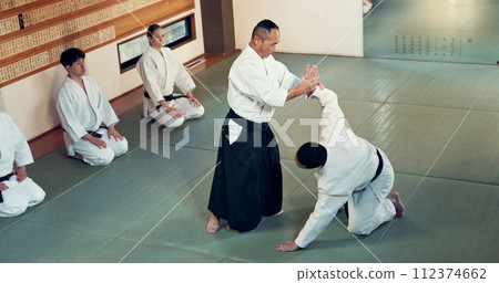 Aikido, class and fight with a master in martial arts with student in self defence, discipline and training. Technique, demonstration or Japanese sensei with black belt skill in fighting or education 112374662
