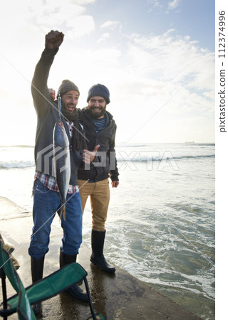 Happy, surprise and people with fish at water with pride for catch of tuna on pier at sunset. Fishing, friends and fisherman smile with shock at success in nature at sea on holiday or vacation 112374996