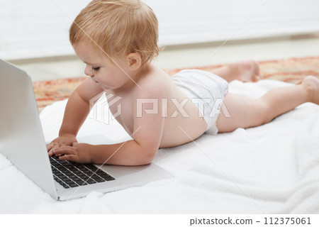 Baby, playing and learning on laptop in home on bed with online games for education. Child, typing and relax with cartoon, movies or development of knowledge of technology with elearning for growth 112375061