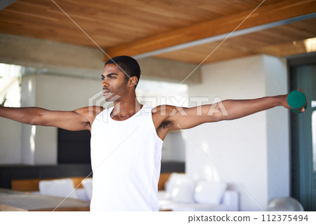 Fitness, yoga and black man in home with weights for wellness, strength and balance for healthy body. Training, pilates and person with equipment for stretching, workout and exercise in living room Fitness, yoga and black man in home with weights for wellness, strength and balance for healthy body. Training, pilates and person with equipment for stretching, workout and exercise in living room 112375494