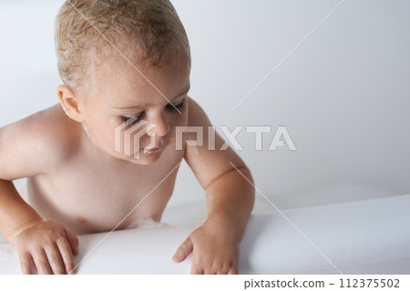 Kid, baby and boy in bathtub of water for morning routine, skincare and wellness at home in bathroom. Toddler, wet child and washing with soap, foam and bubbles for cleaning, hygiene or mockup space 112375502