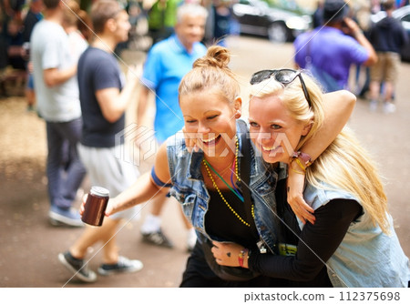 Funny, hug and women with beer, music festival and happiness with weekend break and concert with fun. Laughing, people and friends in a park and woods for an event and party with alcohol and summer 112375698