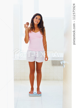 Woman, thinking and scale or weight with cake for healthy body, wellness or weightloss in bathroom at home. Person, stress or snack on weighing machine for health, goals and fitness progress in house Woman, thinking and scale or weight with cake for healthy body, wellness or weightloss in bathroom at home. Person, stress or snack on weighing machine for health, goals and fitness progress in house 112375924