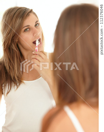 Mirror, brushing teeth and face of woman in bathroom for morning dental cleaning routine. Getting ready, reflection and girl with toothbrush, toothpaste and mouth care in home. Mirror, brushing teeth and face of woman in bathroom for morning dental cleaning routine. Getting ready, reflection and girl with toothbrush, toothpaste and mouth care in home. 112376046