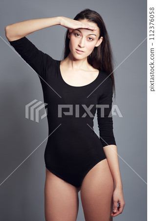 Portrait, hand and woman in leotard for beauty, fashion and ballet in studio isolated on a gray background. Bodysuit, style and young model, ballerina and confident dancer in Spain on a backdrop 112376058