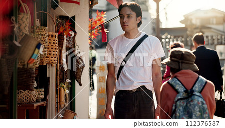 Travel, tourism and man at outdoor street market for holiday, vacation or sightseeing in Japan. City, summer and shopping with confident young tourist in Yokohama town for journey or exploration 112376587