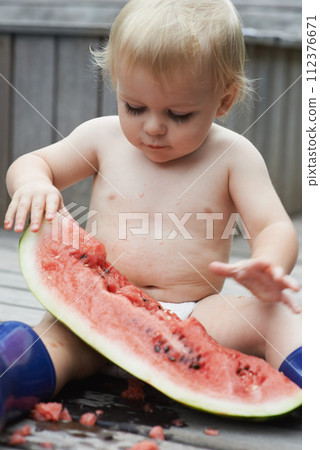 Baby, playing with watermelon and eating, backyard and development with growth, curiosity and home. Toddler, child and infant in garden, alone and childhood for wellness, milestone and coordination 112376671
