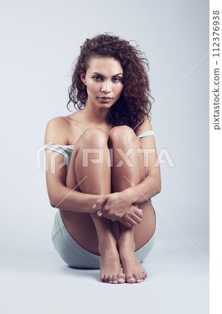 Beauty, portrait and woman sitting in studio on floor with serious confidence and self care on gray background. Casual, cosmetics and model with natural makeup or hairstyle with minimal aesthetic Beauty, portrait and woman sitting in studio on floor with serious confidence and self care on gray background. Casual, cosmetics and model with natural makeup or hairstyle with minimal aesthetic 112376938