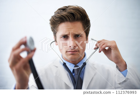 Stethoscope, serious and portrait of doctor in office for medical consultation at hospital. Doubt, thinking and professional young male healthcare worker with equipment for career at medicare clinic Stethoscope, serious and portrait of doctor in office for medical consultation at hospital. Doubt, thinking and professional young male healthcare worker with equipment for career at medicare clinic 112376993