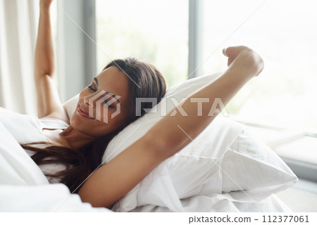 Woman, smile and stretching in bed at house, home and bedroom for waking up, morning and relax after sleep in South Africa. Female person, lady and laying by window with pillow, sheet and happy Woman, smile and stretching in bed at house, home and bedroom for waking up, morning and relax after sleep in South Africa. Female person, lady and laying by window with pillow, sheet and happy 112377061