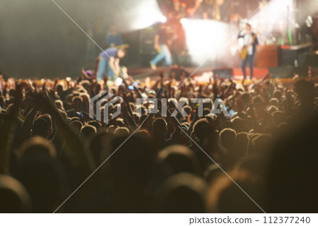 Crowd, live concert and stage with dancing audience as music festival for entertainment, performance or carnival. People, hands and fans of musicians with lighting for rock event, rave or vacation 112377240