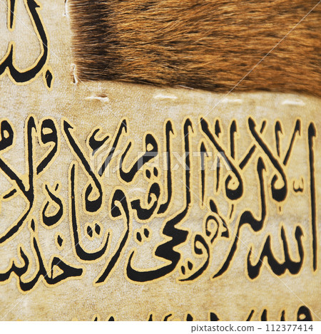 Islamic calligraphy characters on skin leather with a hand made calligraphy pen, the names of Allah (God) are written in arabic Islamic calligraphy characters on skin leather with a hand made calligraphy pen, the names of Allah (God) are written in arabic 112377414