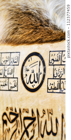 Islamic calligraphy characters on skin leather with a hand made calligraphy pen, the names of Allah (God) are written in arabic 112377459