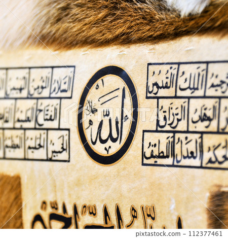 Islamic calligraphy characters on skin leather with a hand made calligraphy pen, the names of Allah (God) are written in arabic 112377461