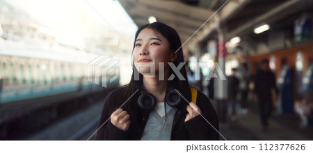 Asian, woman at train station for travel, commute or holiday with smile on face and freedom outdoor. Railway, walking on platform and transportation, journey for adventure in China with happiness Asian, woman at train station for travel, commute or holiday with smile on face and freedom outdoor. Railway, walking on platform and transportation, journey for adventure in China with happiness 112377626