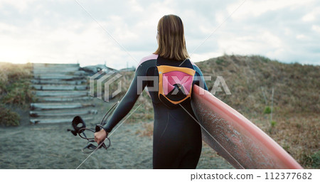 Surfing, beach and back of woman with surfboard for water sports, fitness and freedom by ocean. Nature, travel and person walking on sand on holiday, tropical vacation and adventure by sea in morning 112377682