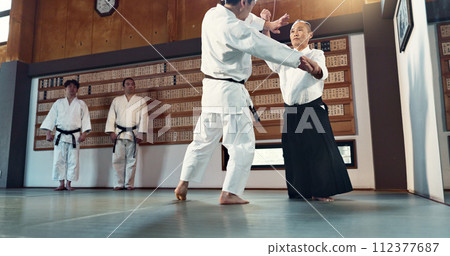 Aikido, sensei and Japanese students with discipline, fitness and action in class for defence or technique. Martial arts, people or fighting with training, uniform or confidence for culture and skill Aikido, sensei and Japanese students with discipline, fitness and action in class for defence or technique. Martial arts, people or fighting with training, uniform or confidence for culture and skill 112377687