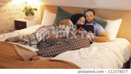 Couple, happy and relax in bedroom with tablet at night, streaming movie and hug. Smile, technology and man and woman in bed on social media app, watching online video and bonding together in home. Couple, happy and relax in bedroom with tablet at night, streaming movie and hug. Smile, technology and man and woman in bed on social media app, watching online video and bonding together in home. 112378077