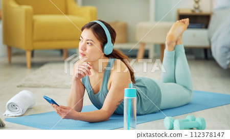 Smartphone, yoga and headphones of woman typing on chat app for fitness communication, social media update or blog writing wellness. Pilates girl with exercise gear and technology in home living room 112378147