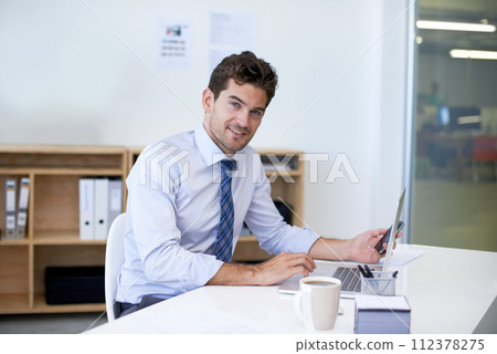Portrait, desk and businessman with phone, laptop and coffee at startup with technology. Smile, online and business analyst in office with computer, smartphone and internet connection for networking 112378275
