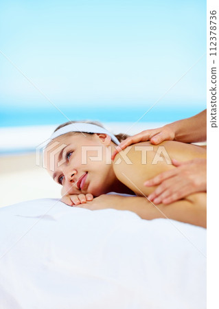 Woman, massage and muscle on bed in spa for health, wellness and recovery with rest, peace and quiet. Girl, mockup space and resort for rehabilitation, blue sky or physical therapy for body fatigue 112378736