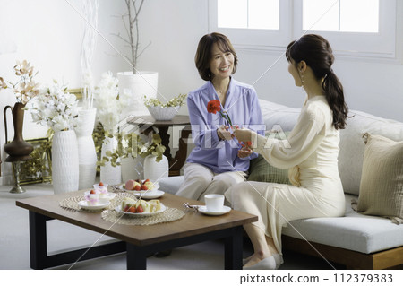 Mother's Day: A daughter in her 30s gives a carnation to her mother in a hotel tea room 112379383