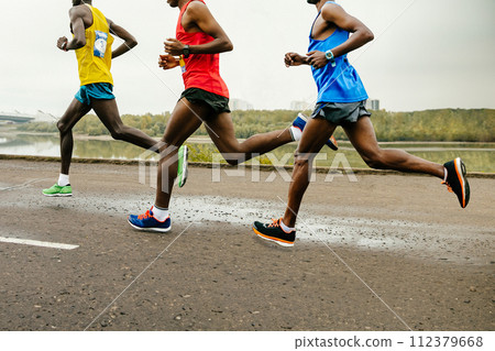 leading group african runners dressed in bright sports clothes race along calm river, summer marathon leading group african runners dressed in bright sports clothes race along calm river, summer marathon 112379668