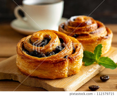 Freshly baked raisin danish and coffee on a wooden board 112379715