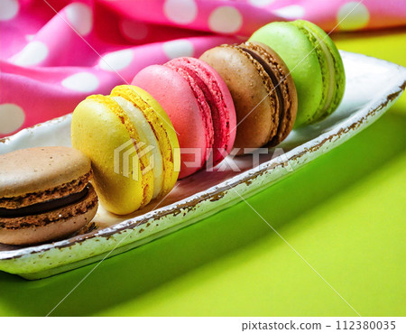 Assortment of colorful macarons arranged on a retro and pop cloth Assortment of colorful macarons arranged on a retro and pop cloth 112380035
