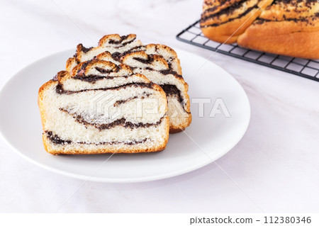 Pastry with poppy seeds, fresh bun on white plate, delicious bakery, light background, close up 112380346