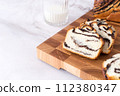 Festive poppy seed roll on wooden board with glass of milk. Fresh sweet bun, white background, homemade pastry 112380347