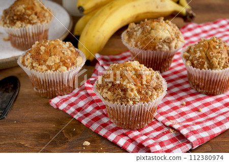 delicious banana muffins on red napkin on wooden table 112380974
