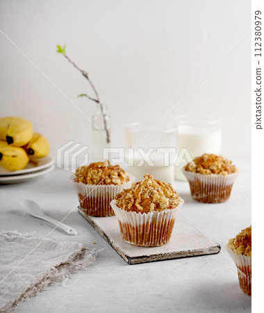 Banana muffins in paper cupcake case with crumble over light table Banana muffins in paper cupcake case with crumble over light table 112380979