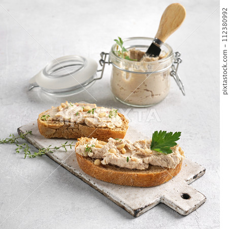 Homemade pate, spread or mousse in glass jar with sliced bread and herbs 112380992